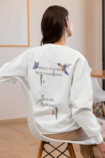 Person wearing a white sweatshirt with colorful designs and text on the back, sitting in a chair.