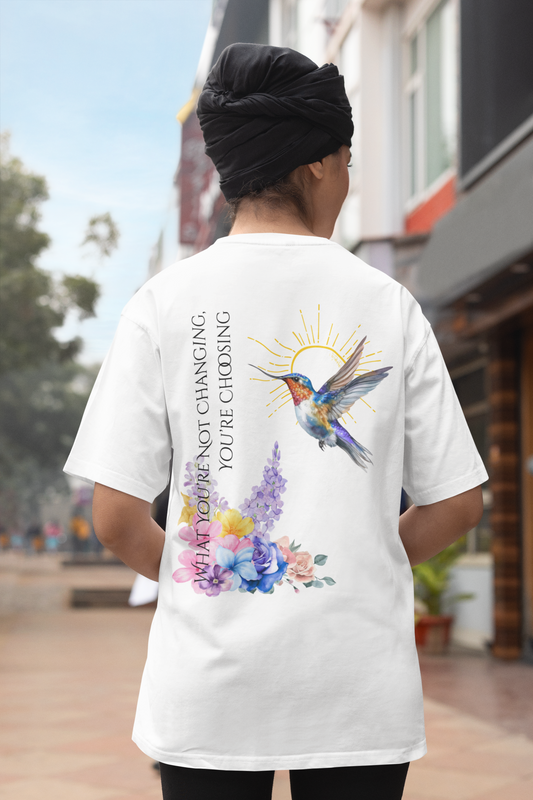 Person wearing a white t-shirt with a colorful design and text, standing outdoors.