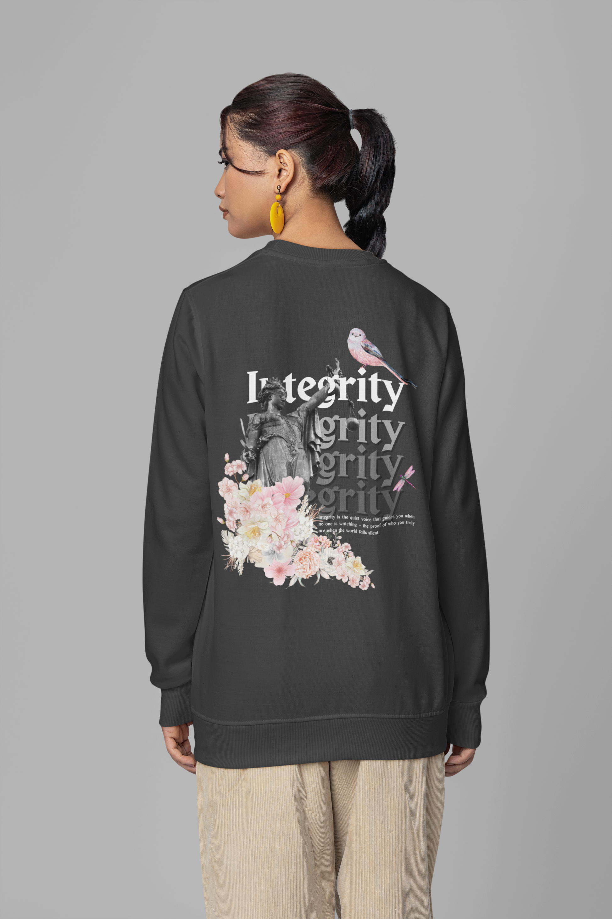 Person wearing a black sweatshirt with floral and text design on a gray background