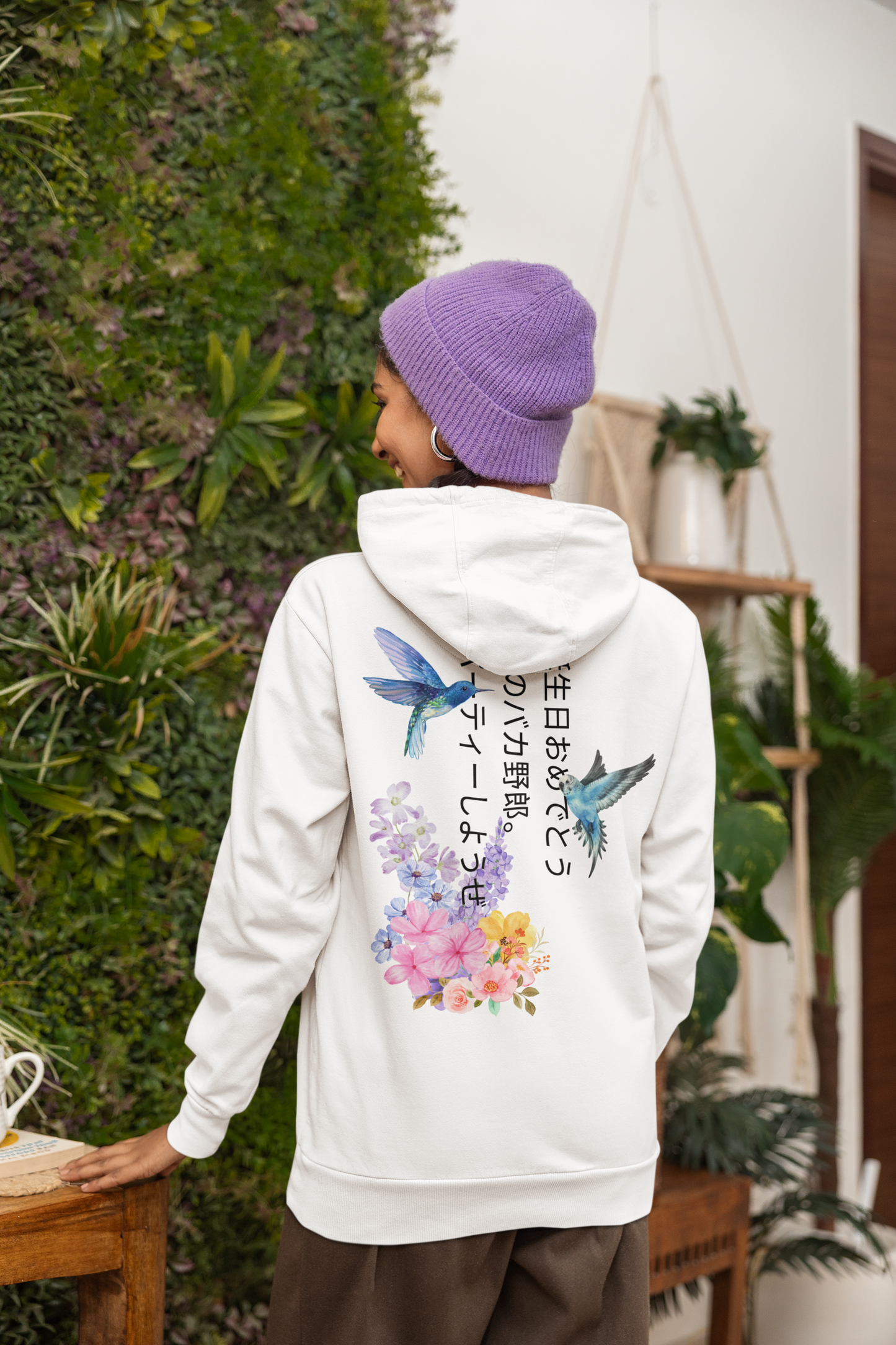 Person wearing a white hoodie with floral and bird designs outdoors
